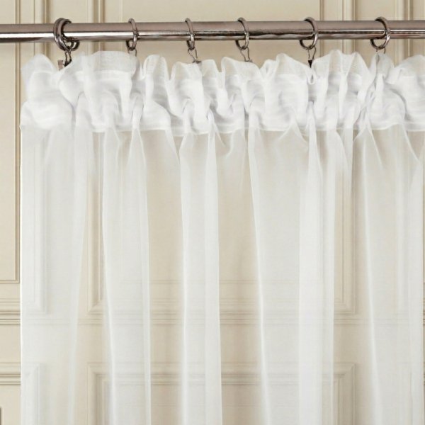 Zbliżenie na górną krawędź firany z tunelem, zamontowanej na cienkim, metalowym karniszu rurkowym.