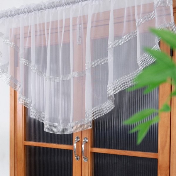 Krótka firana z dwoma pasami cyrkonii zawieszona na drewnianym oknie – widok z bliska.