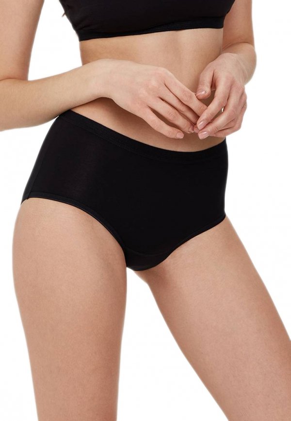 Czarne majtki z wysokim stanem, widok z przodu na modelce. Elastyczny materiał i wysoki stan zapewniają wygodę, a subtelne wykończenie sprawia, że majtki są niemal niewidoczne pod ubraniem.