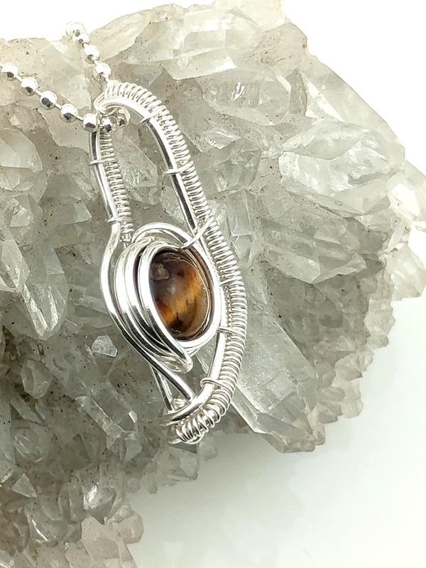 Wisiorek z drutu srebrnego (2.3x1 cm) z tygrysim okiem – kamieniem równowagi pomiędzy skrajnościami, wnikliwości, witalności, siły, praktyczności, uczciwości